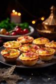 Mini-Quiches mit Schinken und Käse auf einem Teller angerichtet.